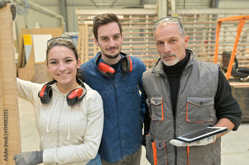 Portrait of man with trainees in carpentry warehouse