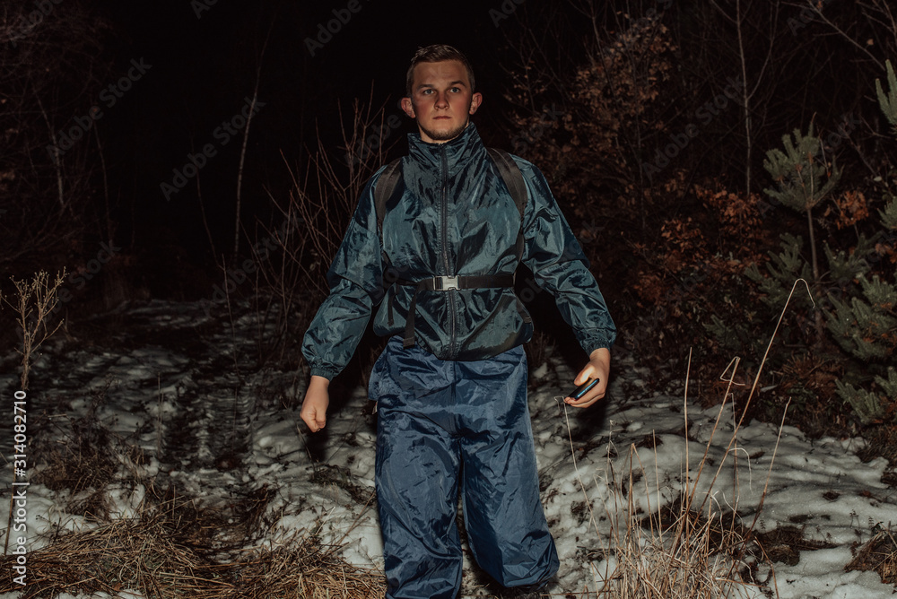 Male hikers in clothes for hiking and flashlights on winter mountain at night.
