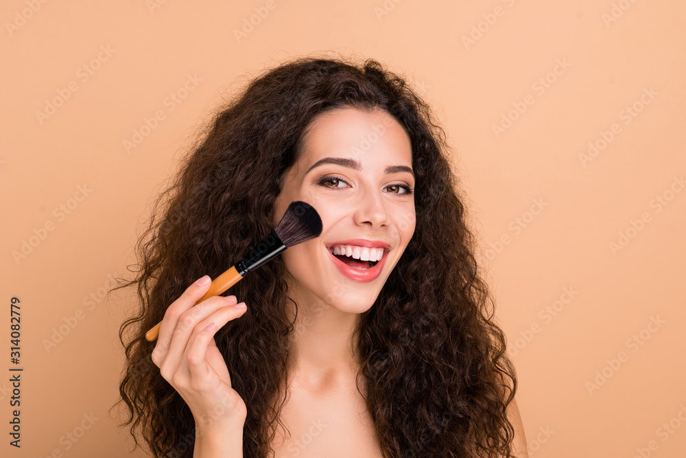Close-up portrait of her she nice-looking charming cute lovely attractive shine lovable nagnificent cheerful cheery glad wavy-haired girl applying highlighter isolated on beige background Close-up portrait of her she nice-looking charming cute lovely attractive shine lovable nagnificent cheerful cheery glad wavy-haired girl applying highlighter isolated on beige background