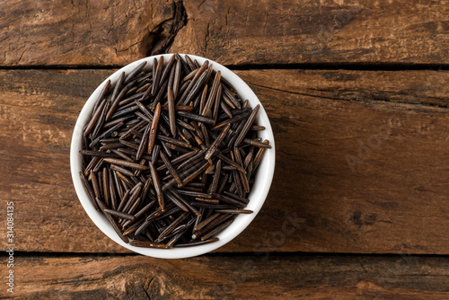 Wild rice in bowl on rustic wooden table. Top view