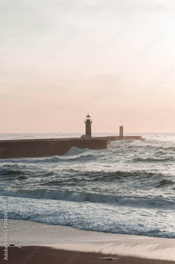 Fototapeta premium Ocean at sunset, behind the lighthouse. Lighthouse as a Landmark. Vertical photo
