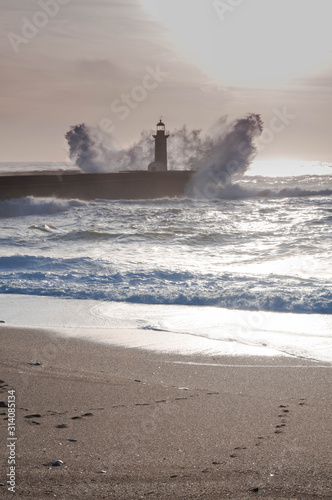  Big waves break down to the pier under the lighthouse. Sunset Lighthouse. Lighthouse as a Ladmark. Foz do Douro. Porto. Portugal. Vertical photo