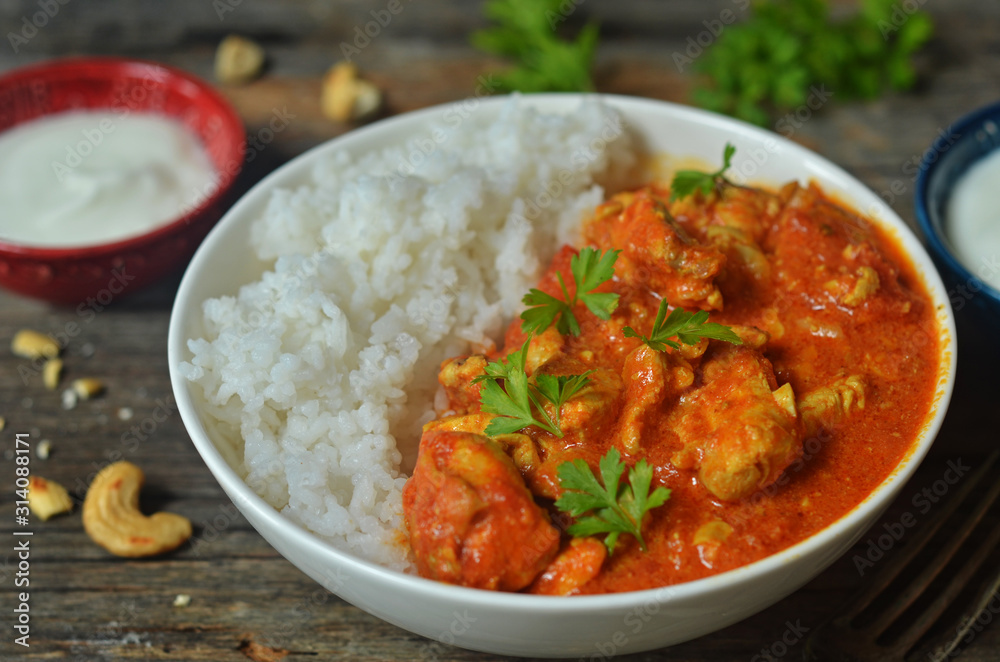 Butter chicken with rice in a bowl on a wooden background