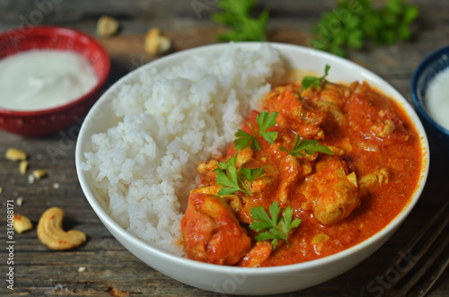 Butter chicken with rice in a bowl on a wooden background