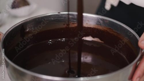 The housewife is stirring melted chocolate with a spatula. She is cookong homemade chocolate. photo