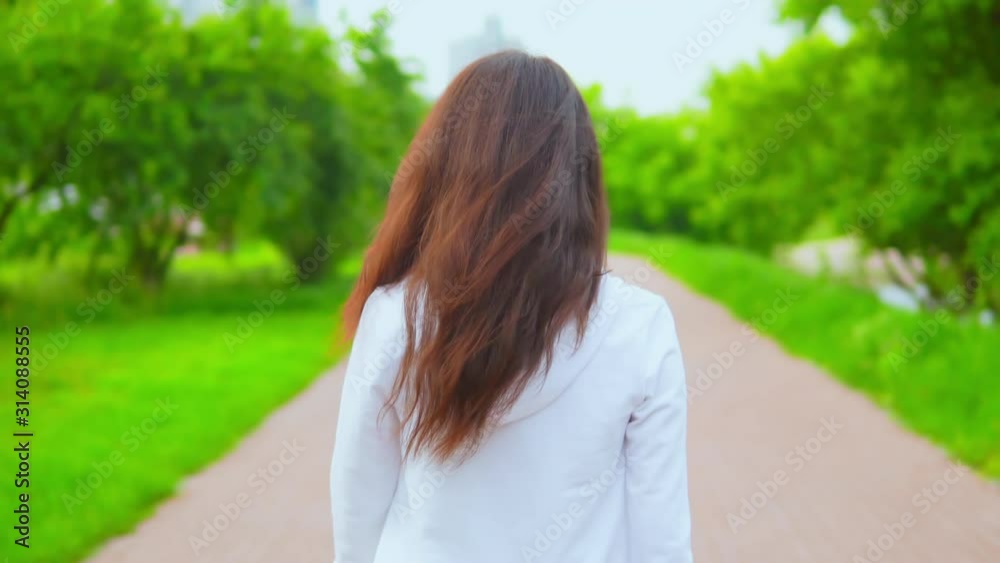 caucasian woman back view turn to the camera her young face with cheerful smile female face in spring park with green nature caucasian woman back view turn to the camera her young face with cheerful smile female face in spring park with green nature