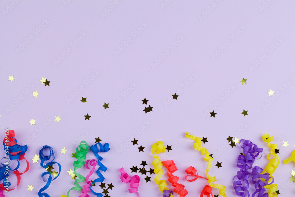 Festive party border or frame of colorful spiral streamers and confetti on pink background
