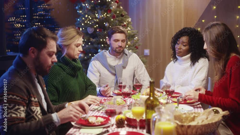 Young attractive men and women friends celebrating New Year, talking and sharing life stories, enjoying company and winter holidays together.