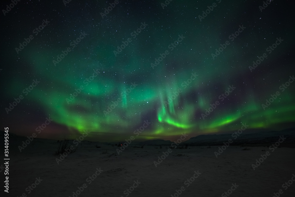 Dramatic polar lights, Aurora borealis with many clouds and stars on the sky over the mountains in the North of Europe - Abisko, Sweden. long shutter speed.