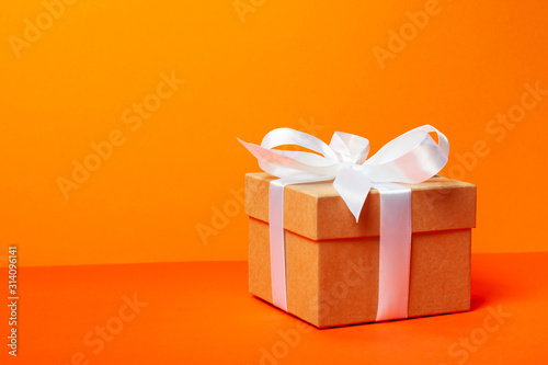 Trendy attractive minimalistic gift on the orange background. Merry Christmas, St. Valentine's Day, Happy Birthday and other holidays concept. photo