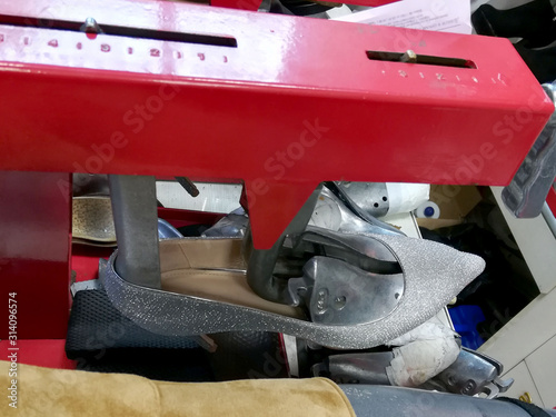 different shoes put on a special device for changing the size, a small Shoe repair shop photo