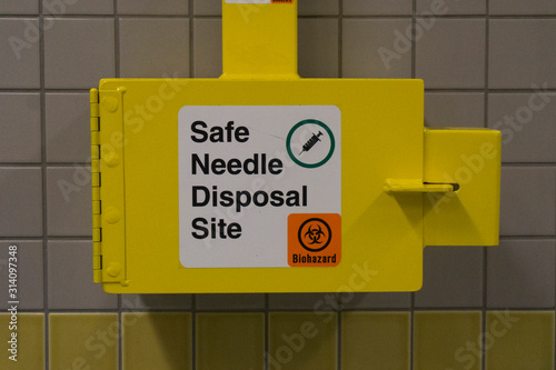 Fotografija Safe medical needle disposal container on a toilet wall