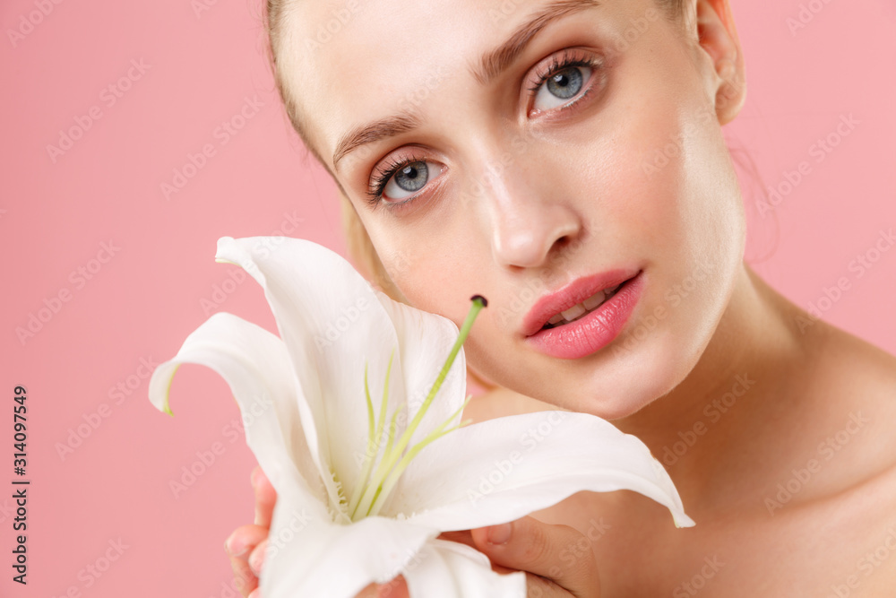 Close up blonde half naked woman 20s perfect skin nude make up blue eyes isolated on pastel pink wall background studio portrait. Skin care healthcare cosmetic procedures concept. Mock up lily flower. Close up blonde half naked woman 20s perfect skin nude make up blue eyes isolated on pastel pink wall background studio portrait. Skin care healthcare cosmetic procedures concept. Mock up lily flower.