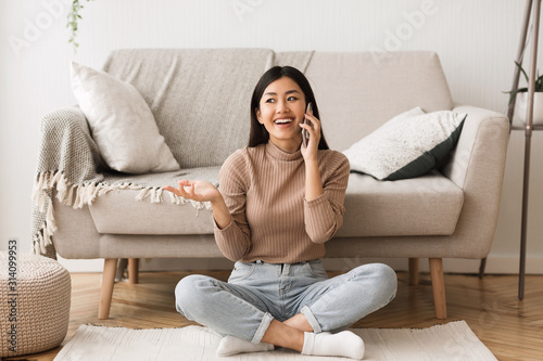 Overjoyed asian girl talking on cellphone with friend