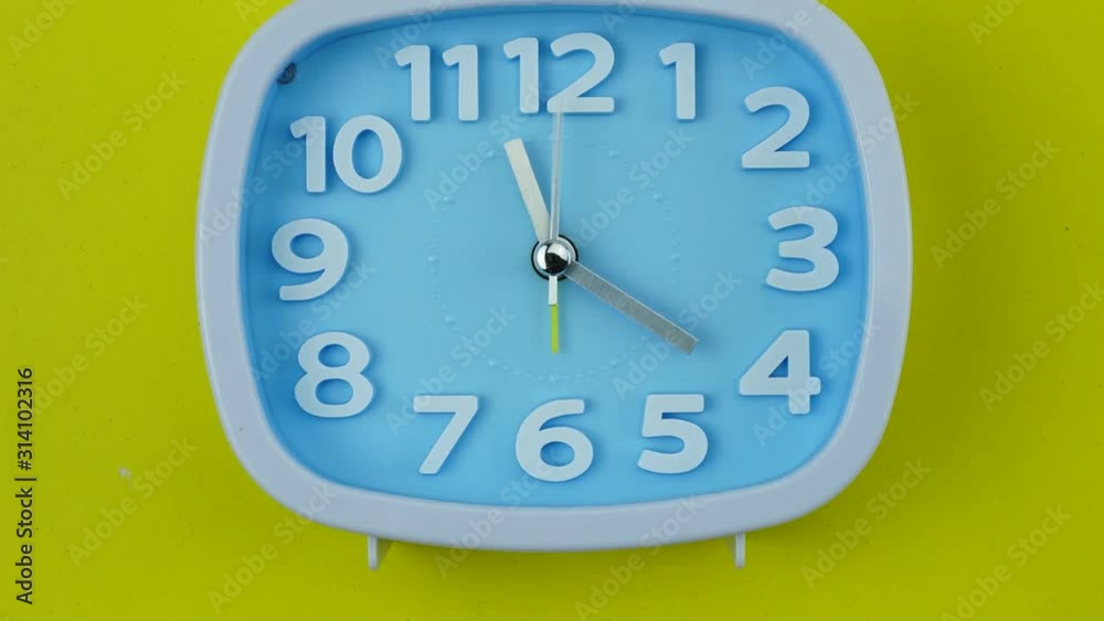 Blue Alarm clock on yellow background, Time lapse 60 minutes moving fast, Time concept. Blue Alarm clock on yellow background, Time lapse 60 minutes moving fast, Time concept.