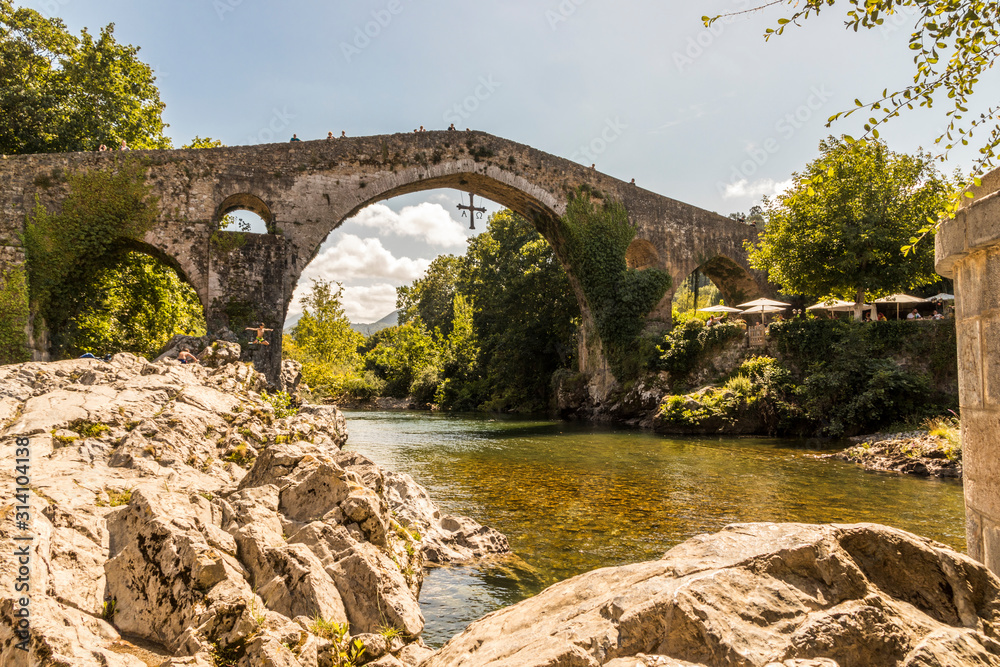 Cangas de Onis, Spain. Boy jumping near the Roman Bridge or Puenton on the Sella River, in the Principality of Asturias