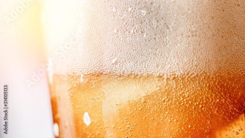 Close up gold blur background texture of yellow lager beer with froth and bubbles in glass, copy space