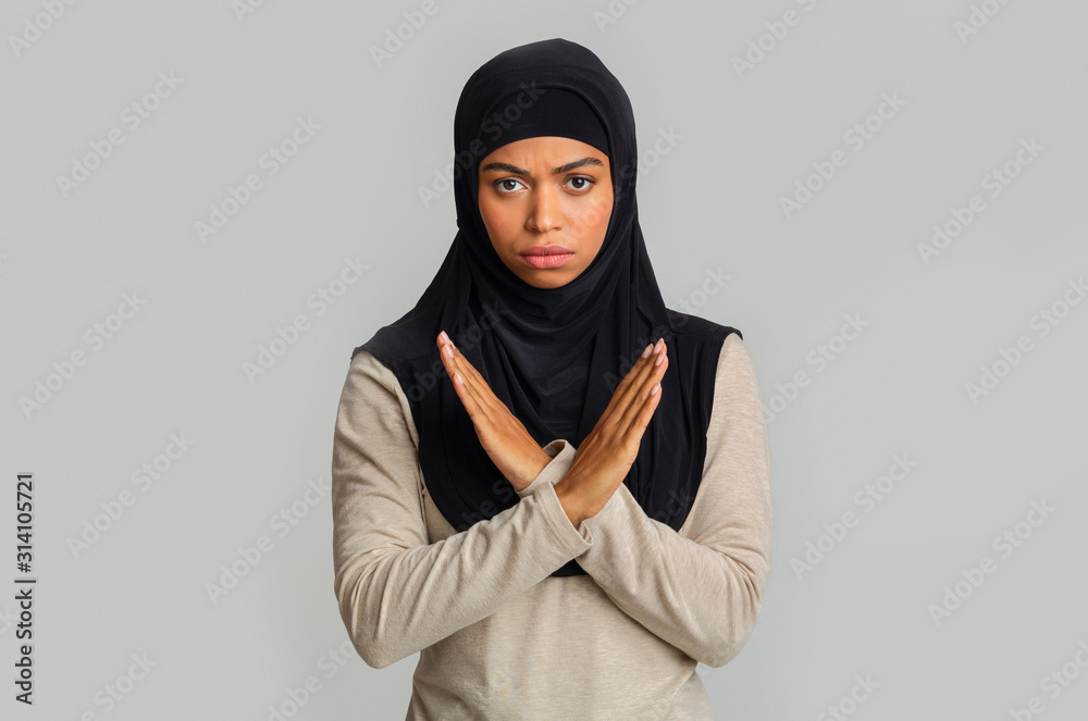 Black muslim woman making denial gesture, keeps arms crossed, rejecting something Black muslim woman making denial gesture, keeps arms crossed, rejecting something