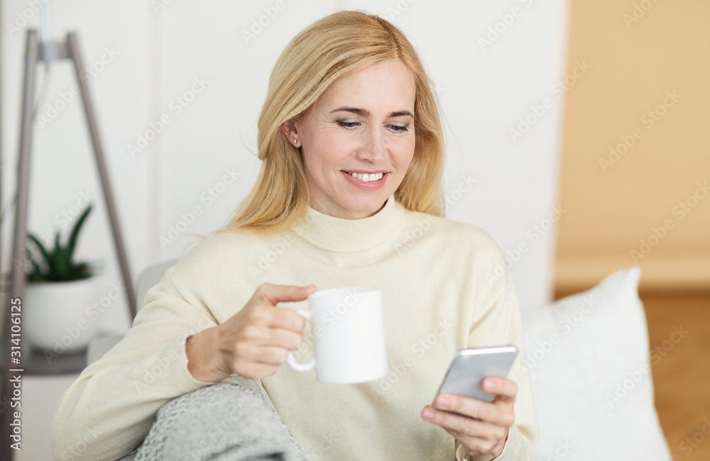 Leisure concept. Middle-aged woman using smartphone and drinking coffee Leisure concept. Middle-aged woman using smartphone and drinking coffee