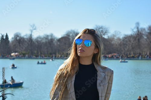 young woman wearing sunglasses and a jacket walking in retiro park in Madrid - Spain © franciscopgr