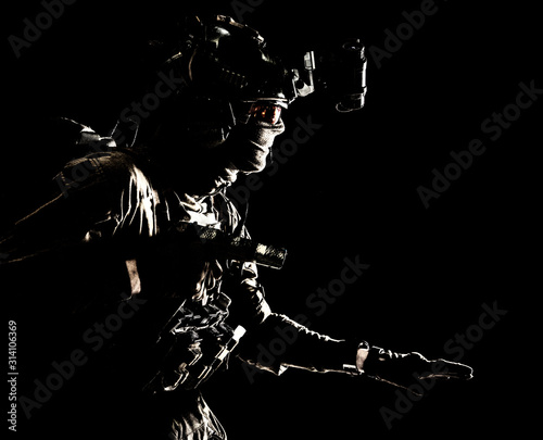 Army special operations soldier, security service fighter, commando shooter equipped modern ammunition, wearing combat helmet, mask and glasses, carefully sneaking in darkness with handgun in hand photo