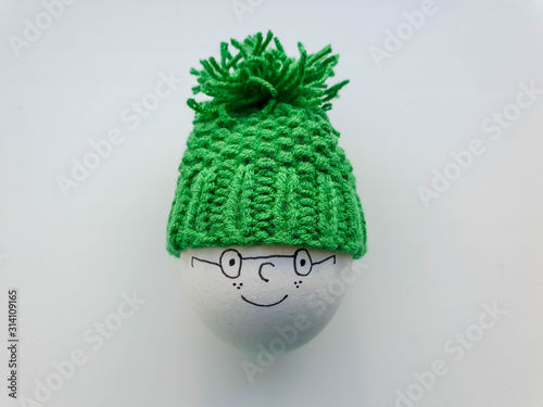 Egg in cute and lovely green knit warmer with bobble. Easter decoration idea. Decor for kids meals.