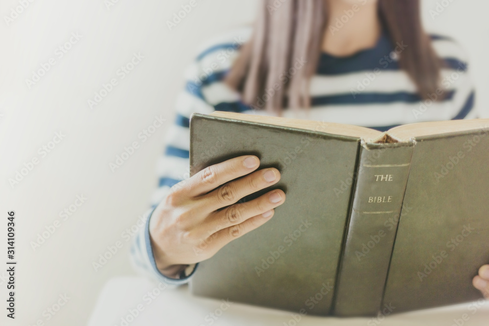 Woman holding the open bible in hands with copy space.