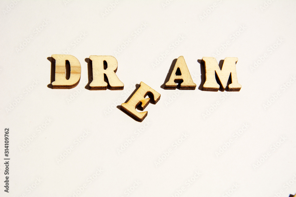 Obraz premium Word Dream written on white background close-up. Broken dreams.