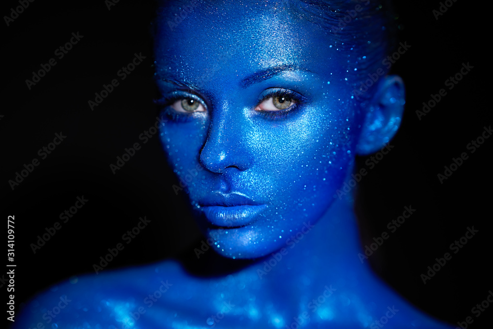 Fashion model woman in blue bright sparkles and neon lights posing in studio.  Portrait of beautiful sexy woman. Art design colorful glitter glowing make up