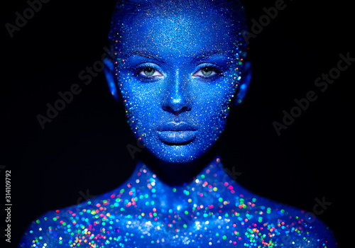 Fashion model woman in blue bright sparkles and neon lights posing in studio.  Portrait of beautiful sexy woman. Art design colorful glitter glowing make up