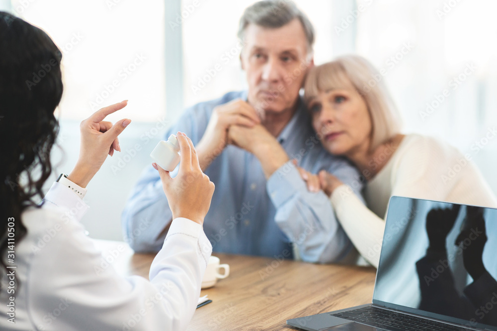 Fototapeta premium Mexican doctor showing pills to elderly couple