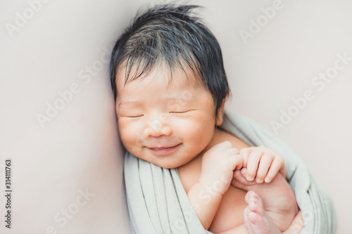 Asian newborn baby sleeping in blanket on bed