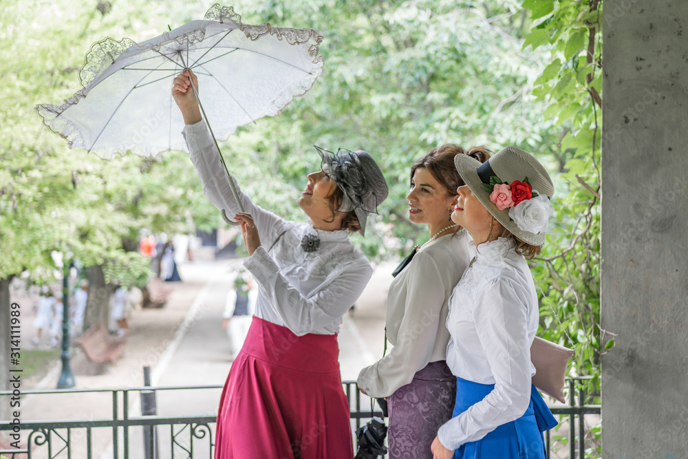 three friends dressed in vintage clothes and umbrella laughing and having fun together