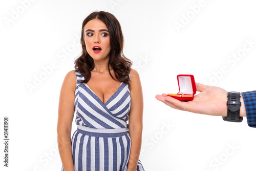 sexy girl in a dress in the neckline and beautiful make-up receives a wedding proposal on a white background