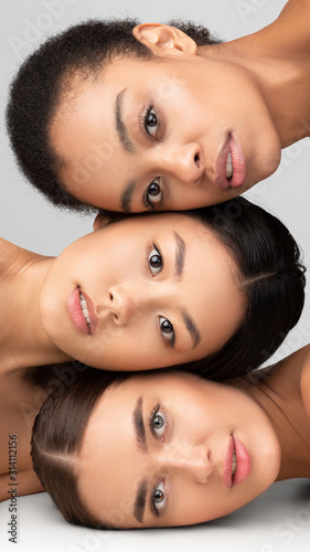 Portrait Of Three Models Girls Posing Over Gray Studio Background