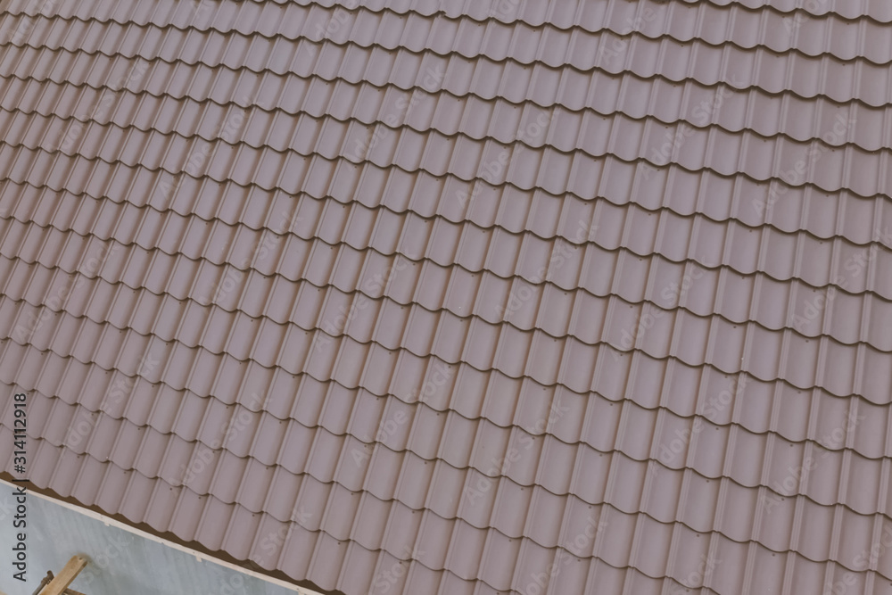 Brown metal tile on the roof of the house. Corrugated metal roof