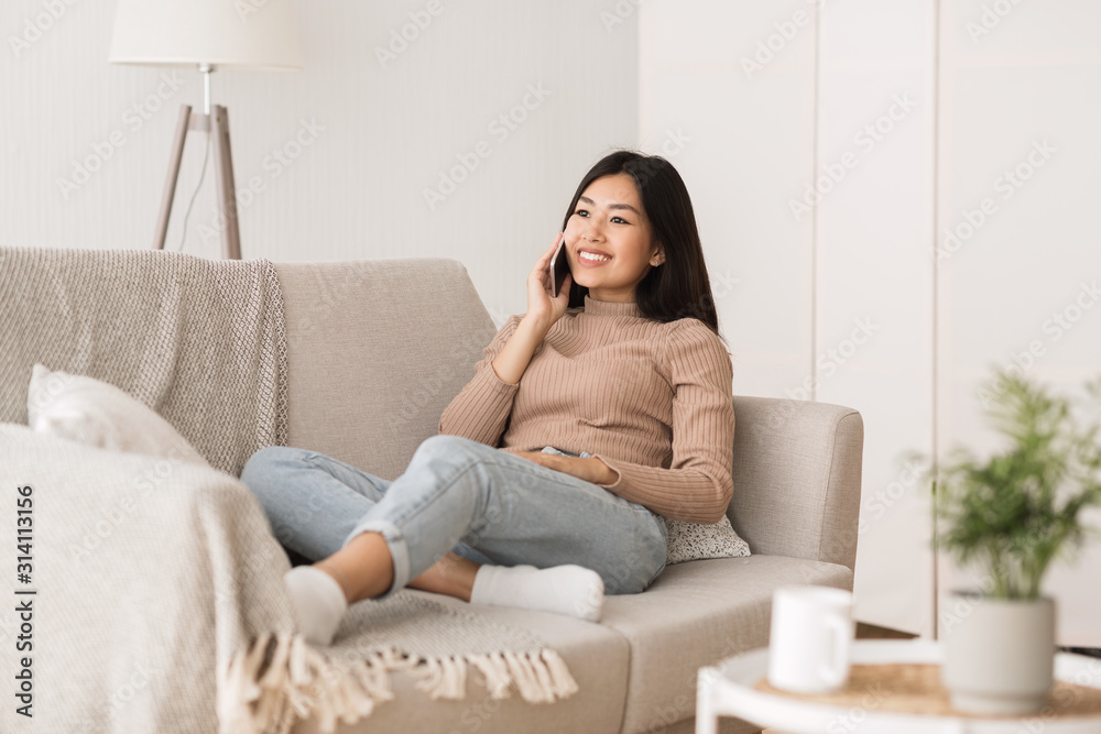 Smiling asian girl chatting on phone with friend Smiling asian girl chatting on phone with friend