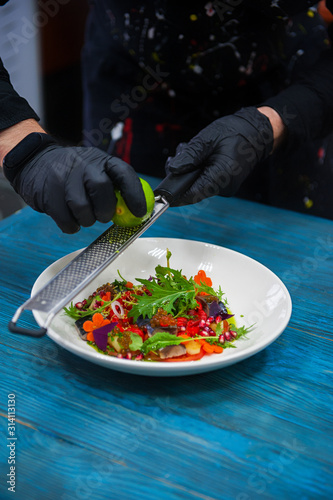 Process of cooking escabeche fish dish with caviar: mackerel in marinade with vegetable, on a plate on the wooden blue background. photo