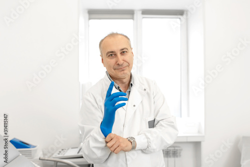 Portrait of a urologist doctor putting on medical gloves before examining a patient