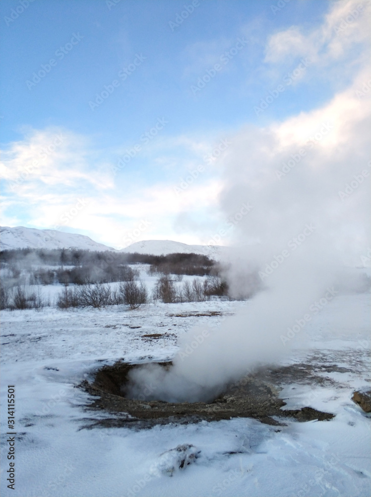 An erupting soaring geyser in the Valley of Geysers. Magnificent Iceland in the winter. An erupting soaring geyser in the Valley of Geysers. Magnificent Iceland in the winter.