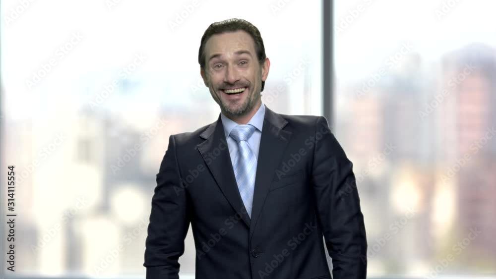 Laughing mature businessman on blurred background. Portrait of joyful caucasian manager looking at camera. Human positive face expression. Laughing mature businessman on blurred background. Portrait of joyful caucasian manager looking at camera. Human positive face expression.