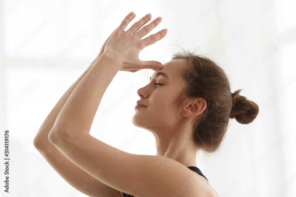 Girl doing meditating exercise with hands together on forehead Girl doing meditating exercise with hands together on forehead