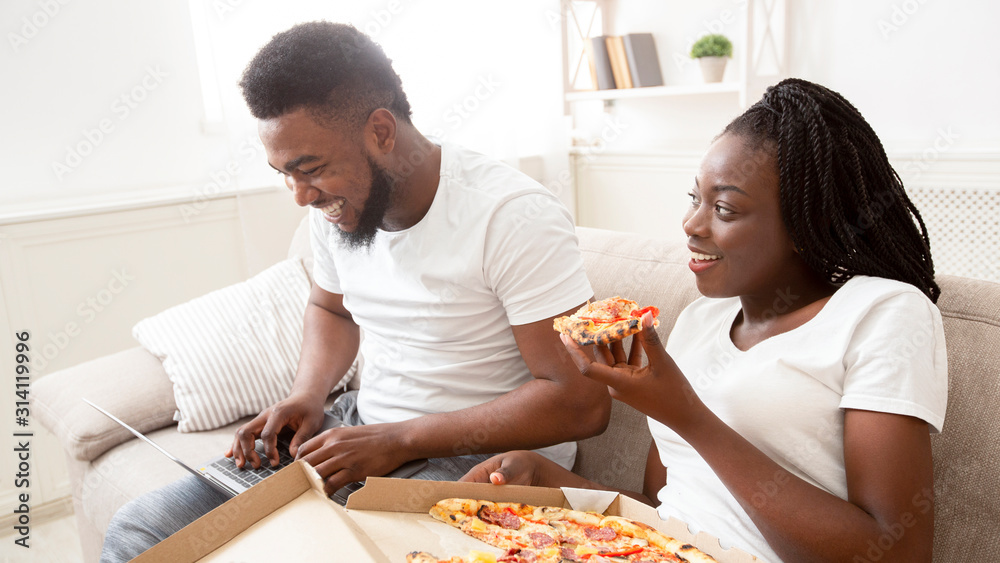 Young afro couple eating pizza and browsing movies on laptop, Young afro couple eating pizza and browsing movies on laptop,