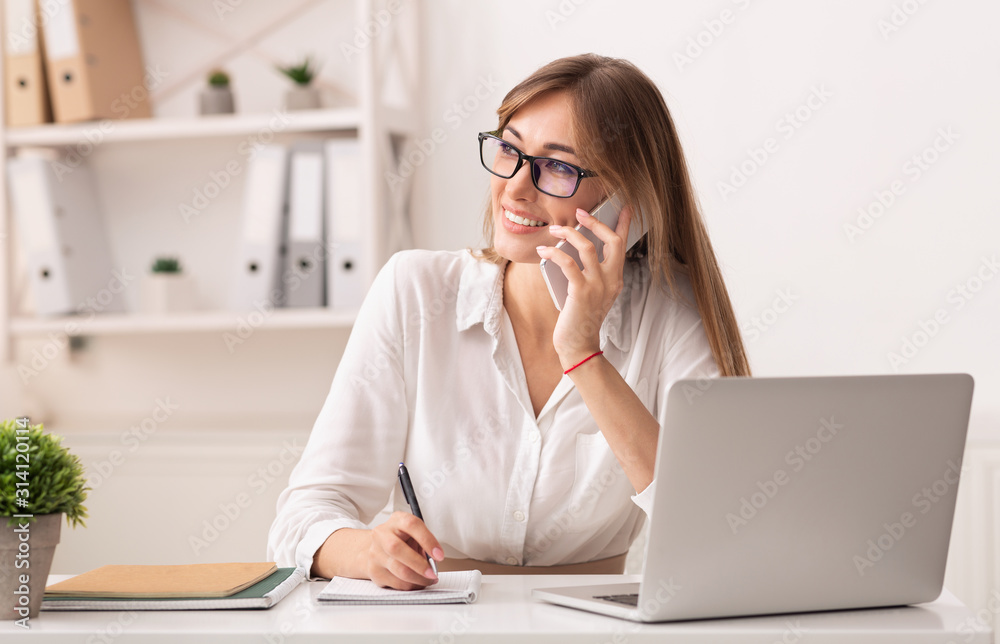 Happy Businesswoman Talking On Phone Sitting At Laptop In Office Happy Businesswoman Talking On Phone Sitting At Laptop In Office