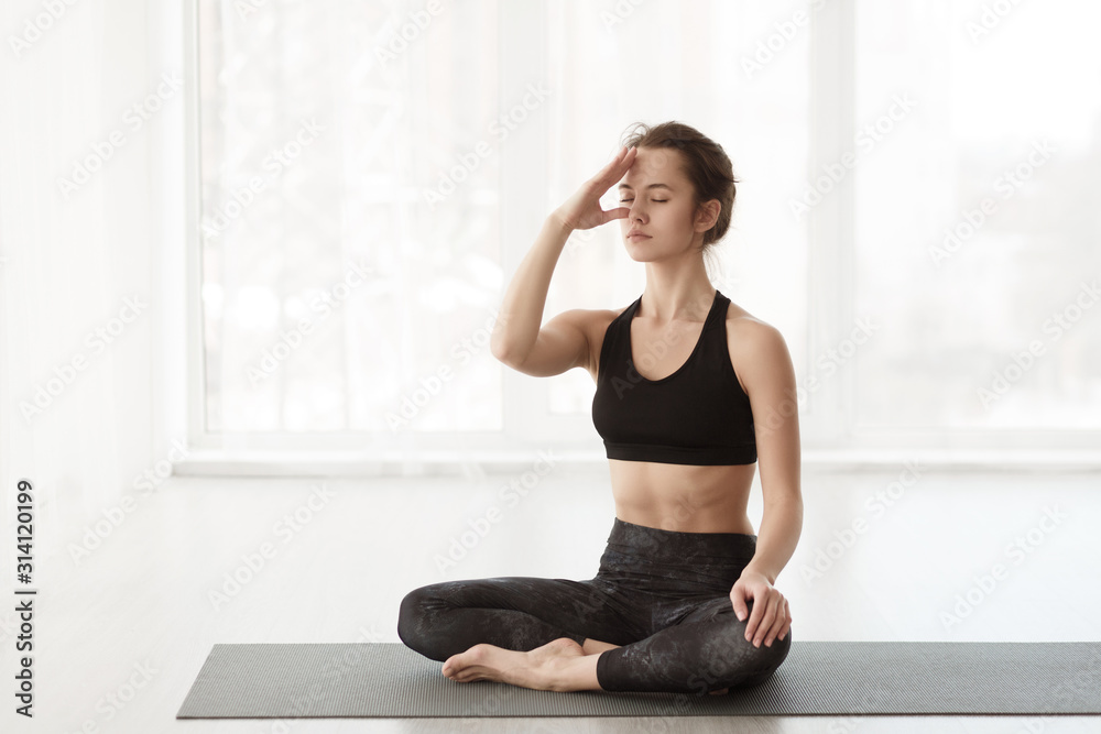 Woman concentrating on thoughts, practicing yoga in studio Woman concentrating on thoughts, practicing yoga in studio