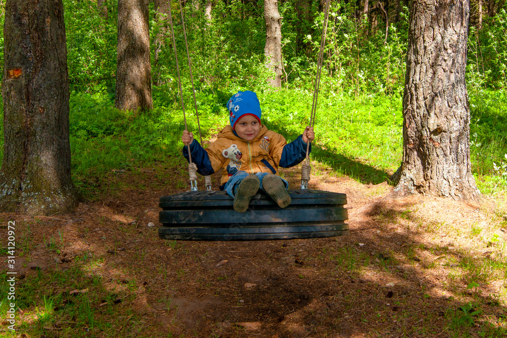 A boy swinging on a swing in the forest