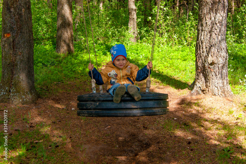 A boy swinging on a swing in the forest
