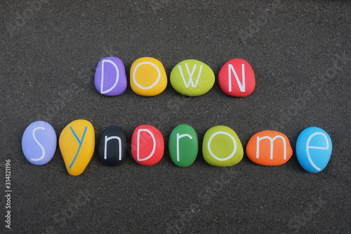 Down syndrome text composed with multi colored stone letters over black volcanic sand