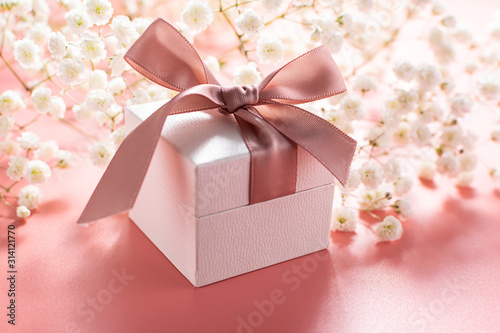 beautiful gift box with bow on pink pastel background with little aromatic flowers. Mother   s Day concept. Valentine   s Day composition.
