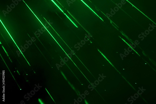 Fotografija Green laser beams with steam and black background